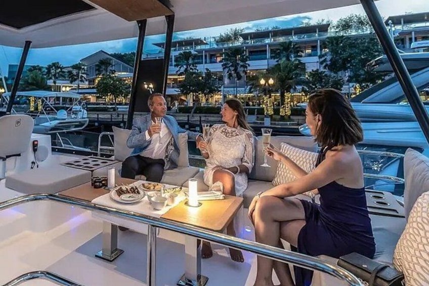 Trois personnes se trouvent sur un yacht, près d’une table à manger, et peuvent admirer la vue sur le port de plaisance. 5