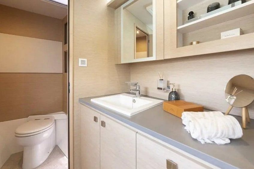 Une salle de bain moderne avec des toilettes blanches, un lavabo et un miroir au-dessus. 2