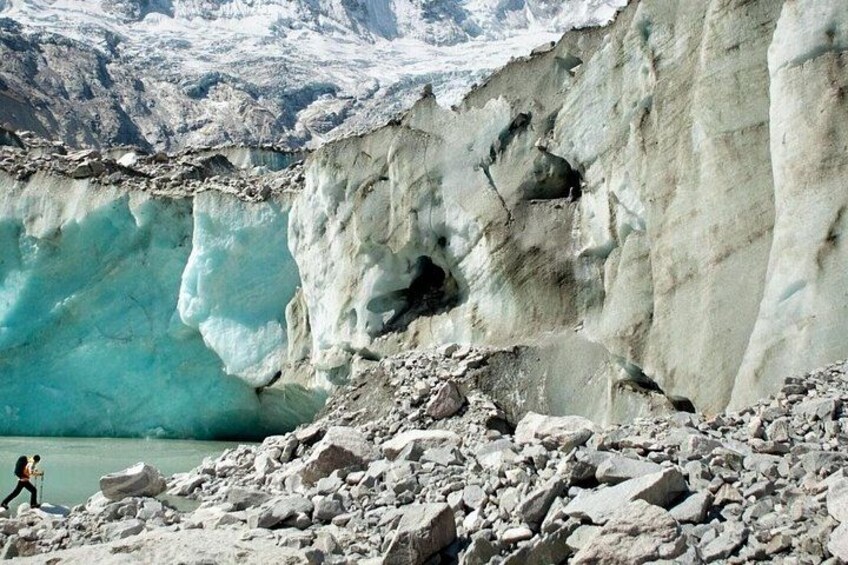 A glacier with a person hiking near its edge. 3