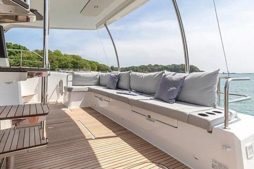 Un pont de bateau doté d’un espace salon avec des sièges rembourrés, d’une table en bois et d’une vue sur l’eau. 2