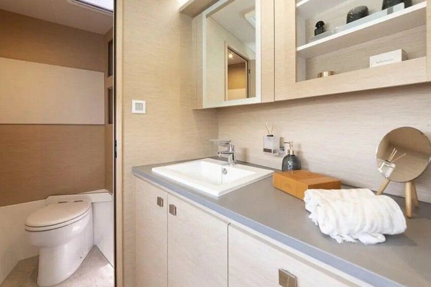 A modern bathroom with a toilet, sink, mirror, and towel rack. 2