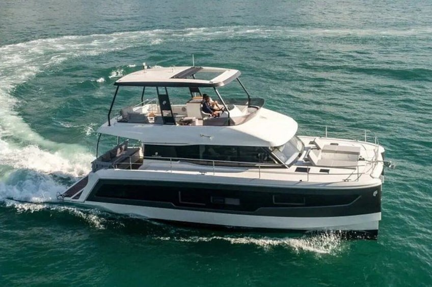 Uno yacht bianco con una cabina e un ponte superiore coperto, che naviga in acque turchesi. 1