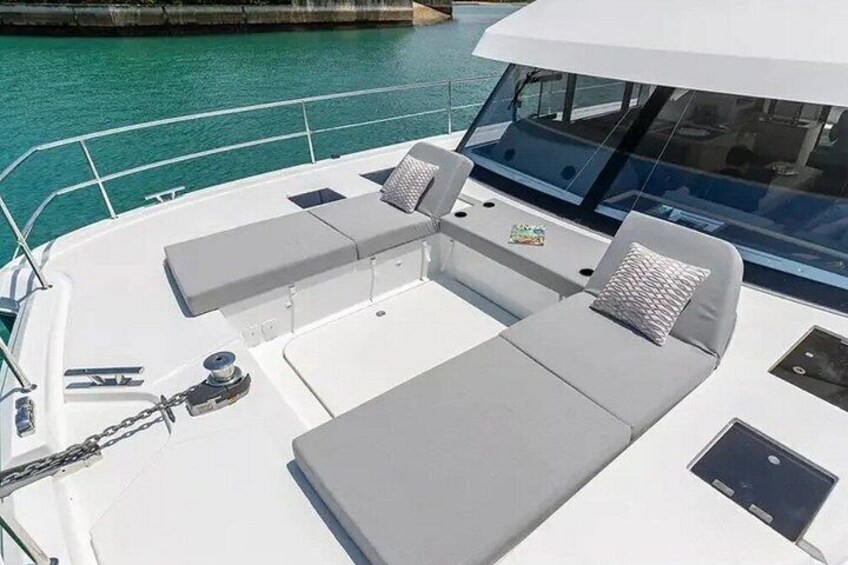 Un bateau avec un pont blanc, des fauteuils de salon gris et une petite table sur laquelle se trouve un livre. 4