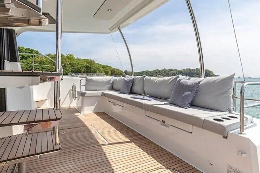 Un pont de bateau doté d’un espace salon, d’une table et offrant une vue sur l’eau et la végétation. 3
