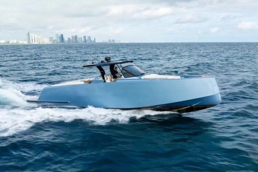 Un bateau élégant et moderne glisse sur l’eau, avec la silhouette d’une ville en arrière-plan. 1