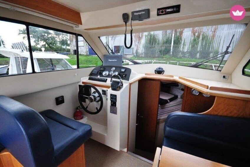 Bootinterieur met een stuurwiel, bedieningspaneel en zitplaatsen. 5