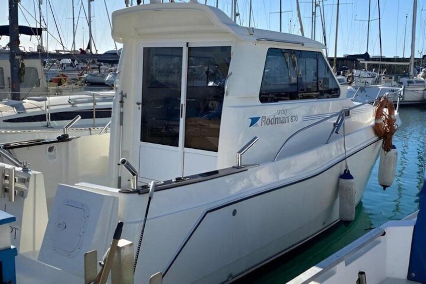 Een witte boot met de naam 'Rodmart 80' ligt aangemeerd in een jachthaven, met andere boten op de achtergrond. 3