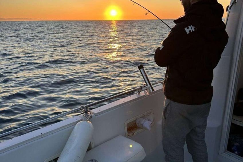 A person fishing on a boat at sunset. 1