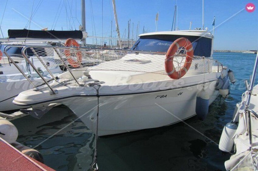 Een witte boot afgemeerd in een jachthaven, met andere boten, drijvers en een helderblauwe lucht. 4