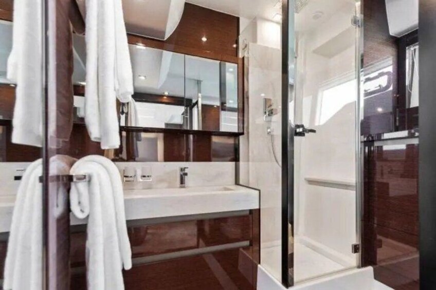 A modern bathroom with a glass shower enclosure, a white sink, and a large mirror. 2