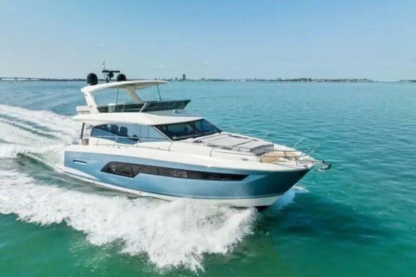 A speedboat on a turquoise sea with a bridge in the background. 1