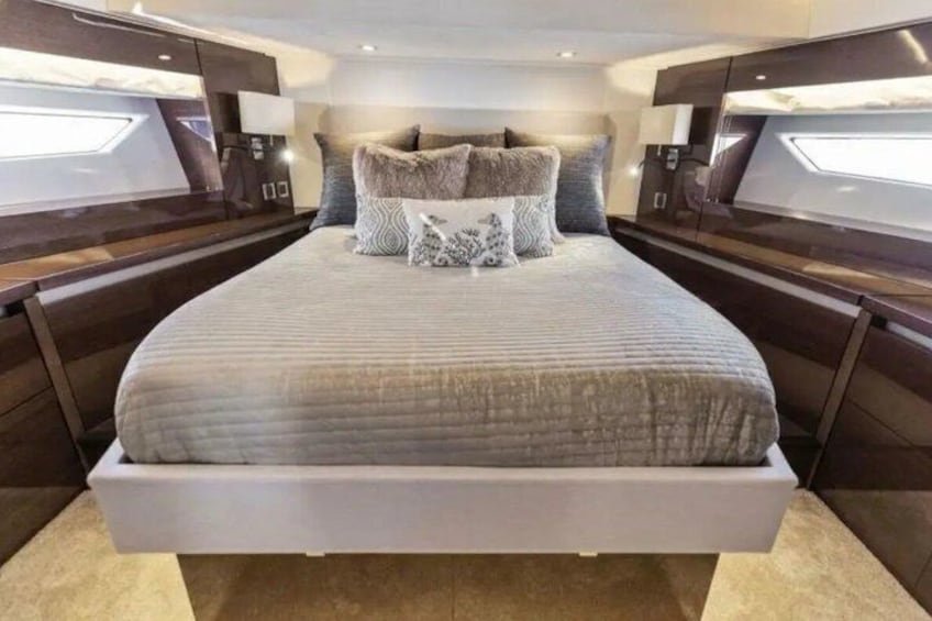 A modern bedroom with a large bed, dark wood furniture, and a view of the ocean. 4