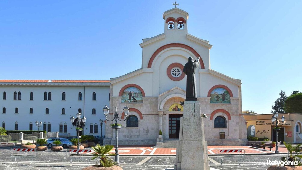 A church with a bell tower and a statue in front. 2