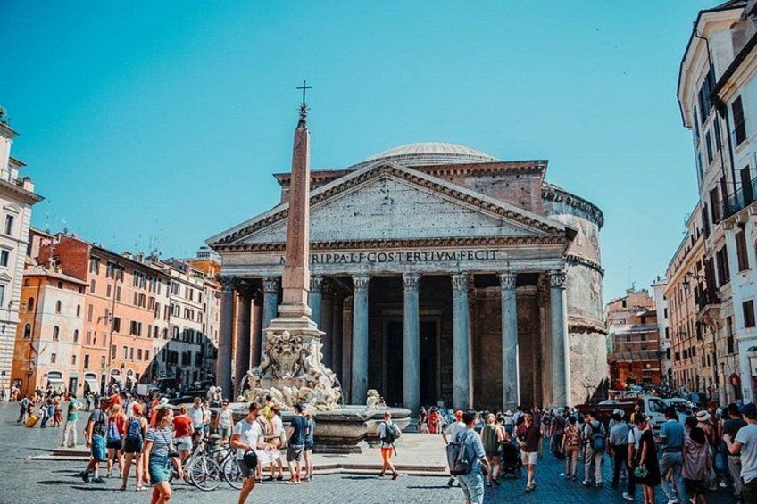 A busy square with a prominent historical building featuring columns and a tall obelisk. 3