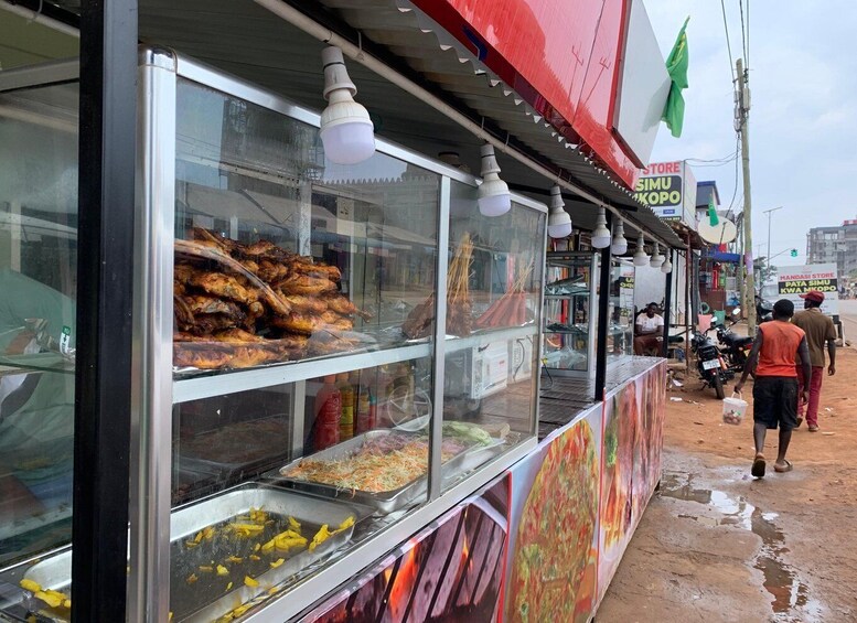 A food stall with grilled meats and vegetables displayed in front of a store. 4