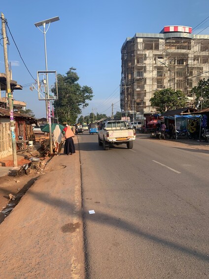 A street with a building under construction, a utility pole, and a few pedestrians. 5