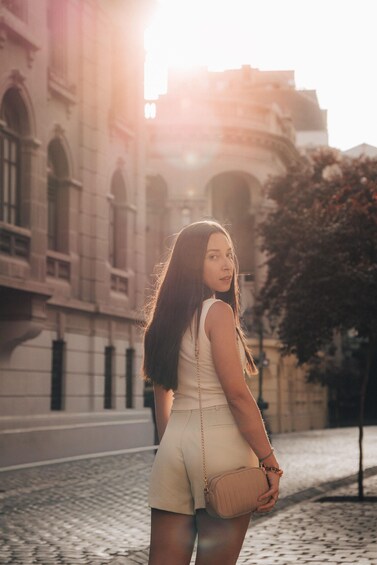 A person standing on a cobblestone street with historic buildings in the background. 5