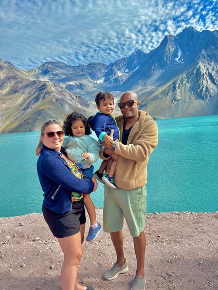 A family by a turquoise lake with mountains in the background. 4