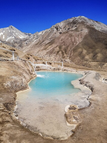 A turquoise hot spring surrounded by rugged mountains. 2