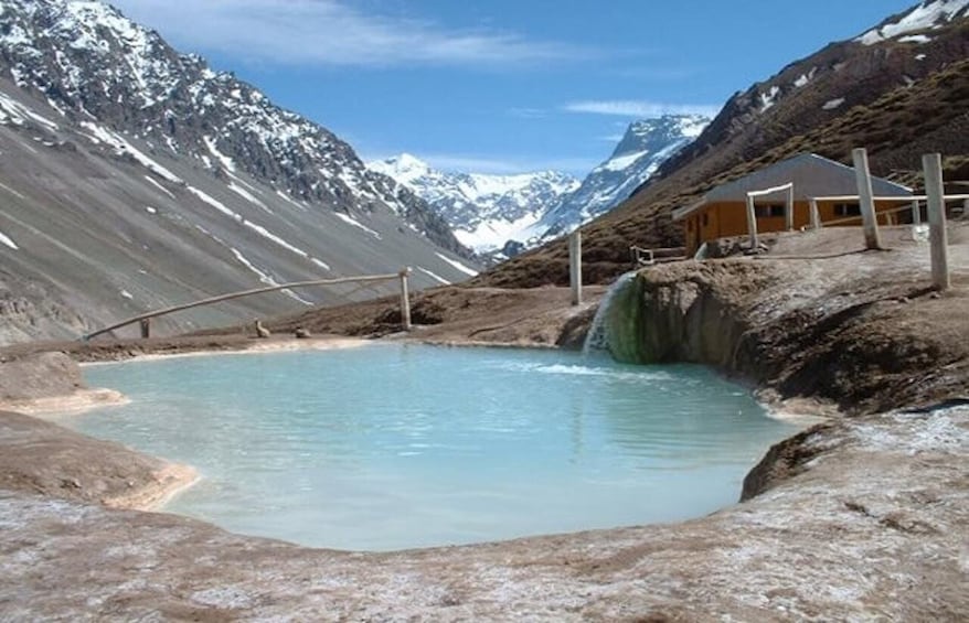 A geothermal hot spring with a wooden cabin in a mountainous landscape. 5