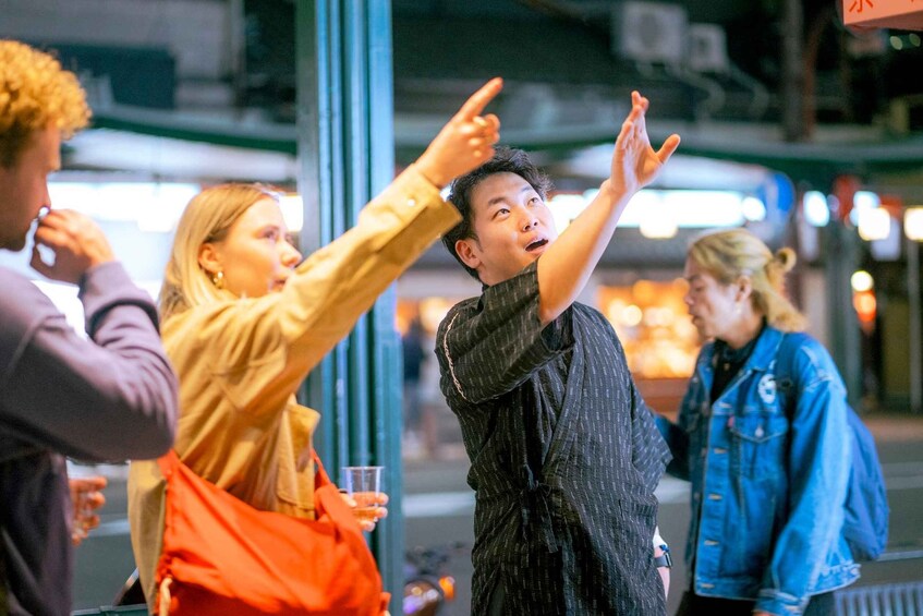 A group of people outdoors at night, some pointing and interacting. 1