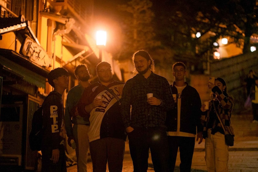 A group of people standing on a street at night. 2