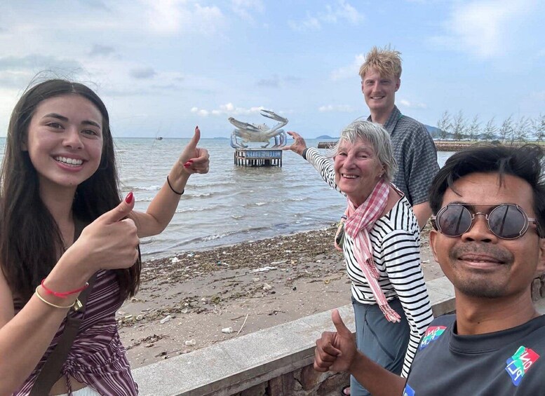 A group of people at a beach with a pier in the background. 4