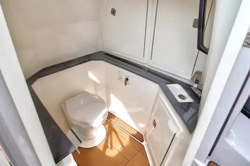 A compact bathroom with a white toilet, a small sink, and a cabinet. 2