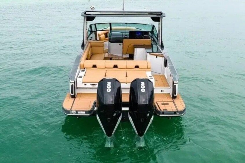 A boat with two outboard motors, a cabin with seating, and a wooden deck. 3