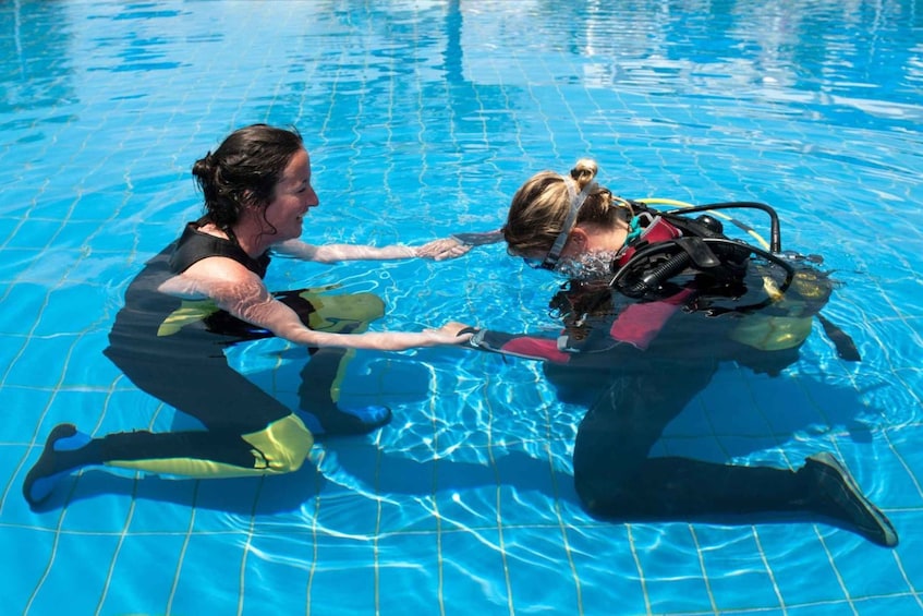 To personer i en pool, hvor den ene hjælper den anden med dykkerudstyr. 2