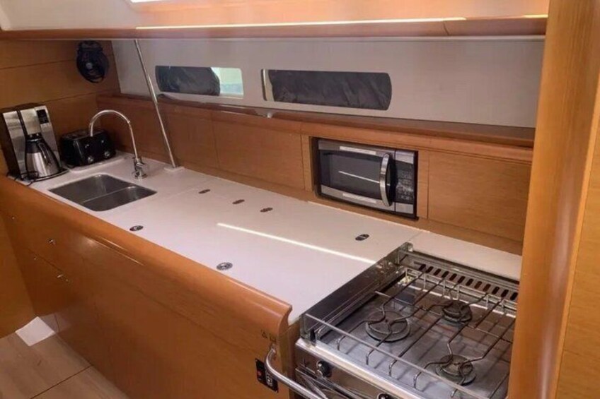 Een kleine keuken met een spoelbak, een magnetron en een kookplaat. 5