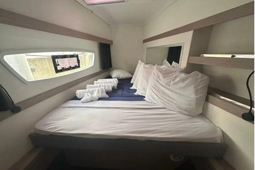 A compact, well-lit interior with a bed, a window, and a small table. 2
