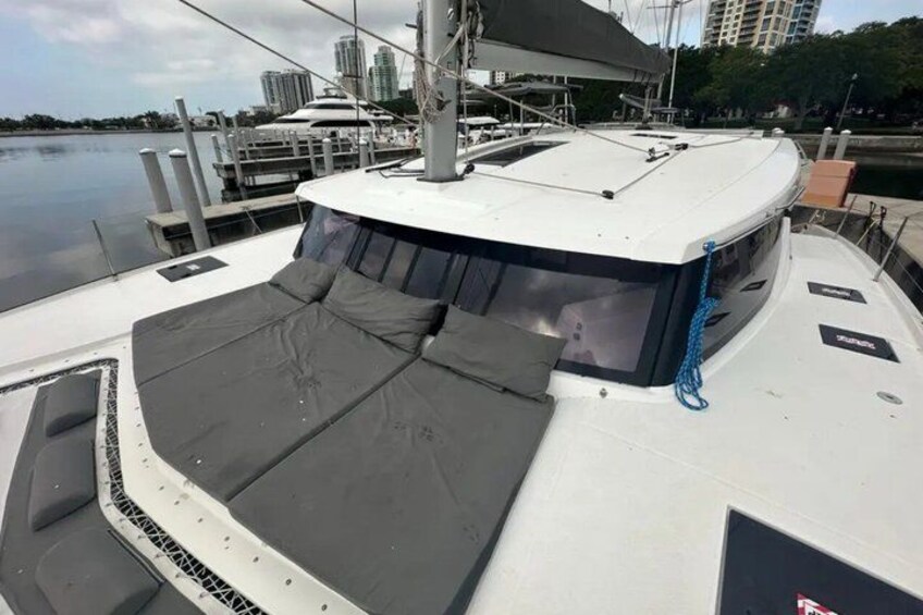 Ponte di una barca con zona salotto coperta, un'antenna e vista sull'acqua e sugli edifici sullo sfondo. 2
