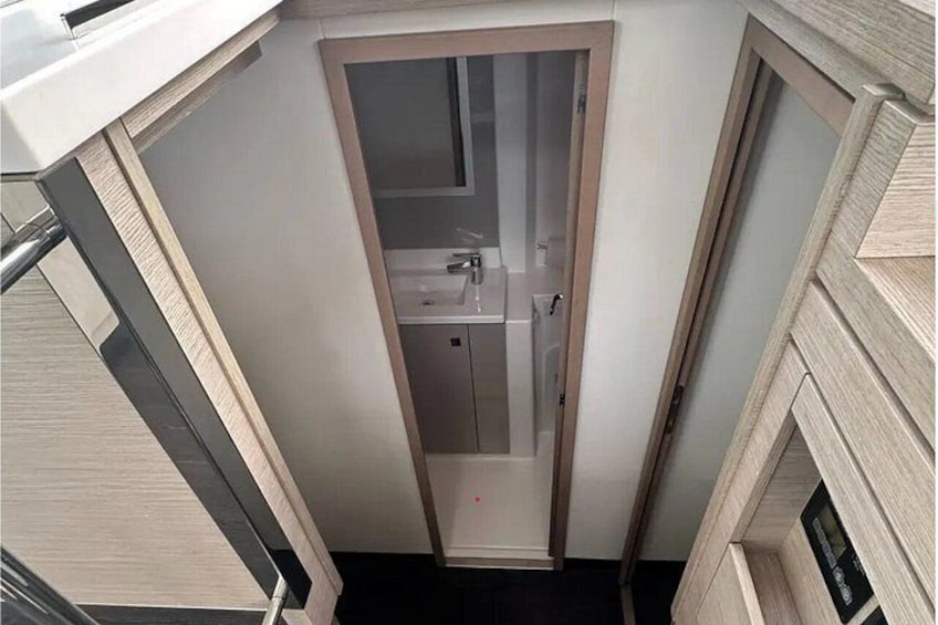 Un espace étroit et fermé, équipé d’un lavabo et d’un miroir, vraisemblablement une salle de bain ou une buanderie. 4