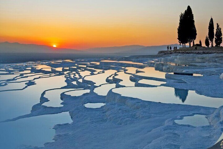 Terraced pools at sunset with silhouettes of trees and people. 2