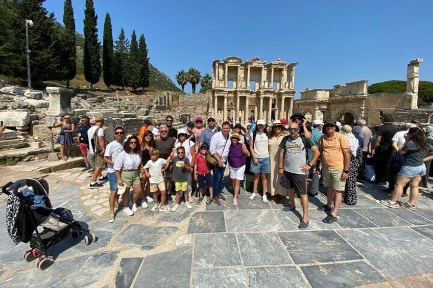 A group of people standing in front of an ancient ruin with columns and a large building in the background. 4