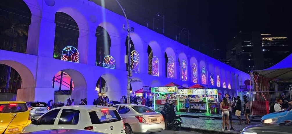 A brightly lit building with arched windows and neon signs. 3