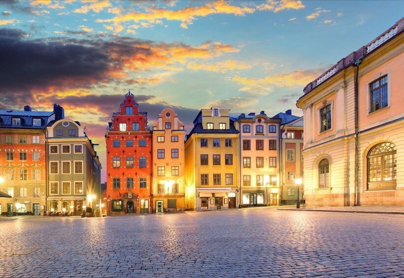 A cobblestone square with colorful historic buildings under a sunset sky. 3