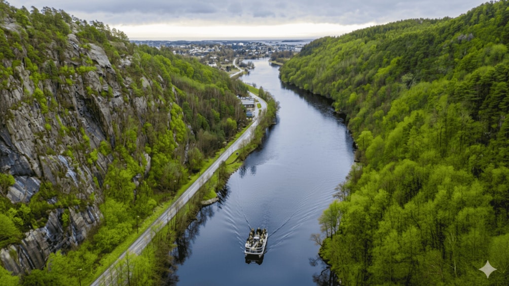 A boat traveling down a river flanked by lush green hills and a road. 1