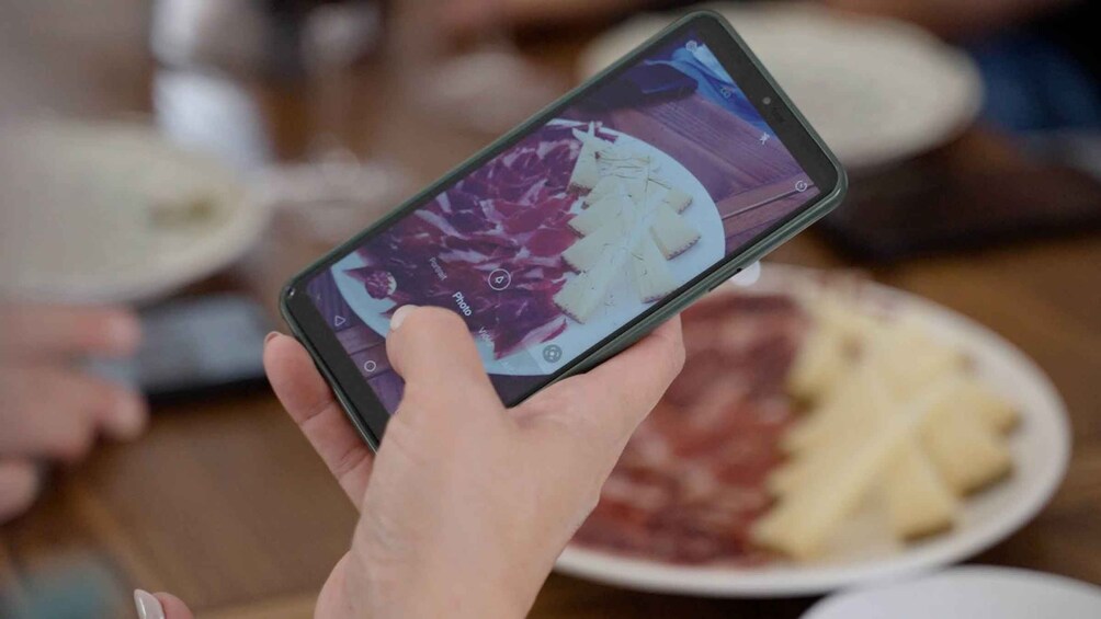 A person holding a smartphone displaying a photo of a dish. 4