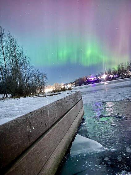 A frozen river with ice floes, a wooden dock, and a view of the northern lights. 5