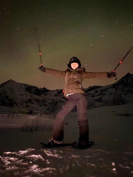 A person standing with arms outstretched in a snowy landscape at night. 1