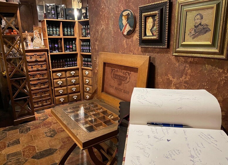 A room with a wooden cabinet filled with bottles, a framed picture on the wall, and a table with a notebook and pen. 4