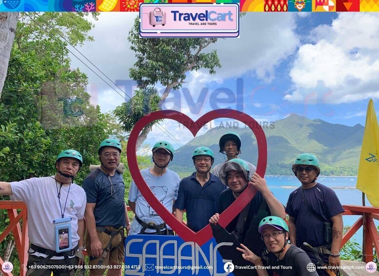 A group of people with helmets, a heart-shaped sign, and a scenic mountain backdrop. 2