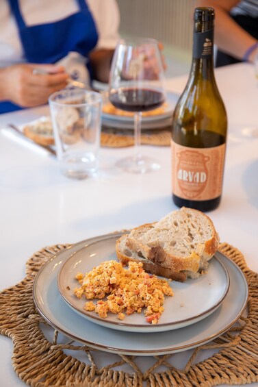 A plate of scrambled eggs with toast, a bottle of wine, and glasses on a table. 5