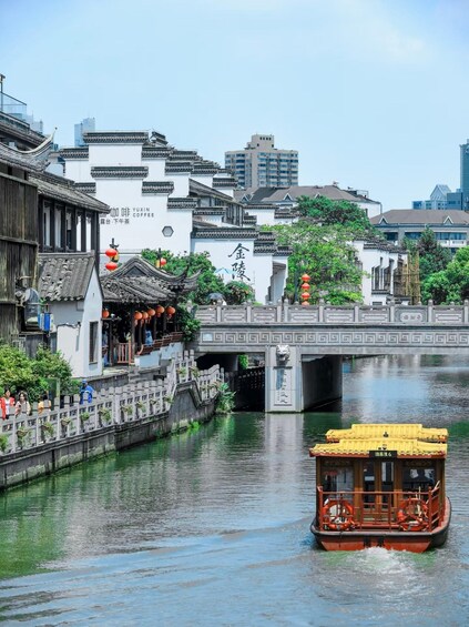 A traditional Chinese waterway with a wooden boat, a bridge, and old-style buildings. 1