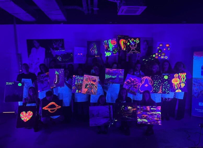 A group of people holding up glowing artwork in a dimly lit room. 3