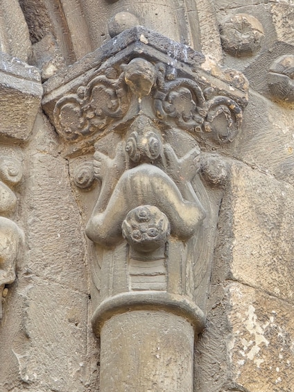 A detailed stone carving of a figure with a headdress, set against a rough stone wall. 2