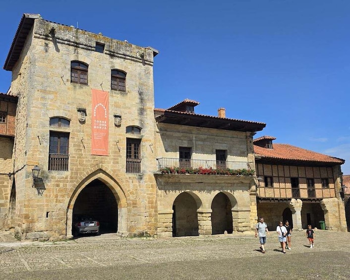 A historic stone building with arched doorways and a red banner. 1