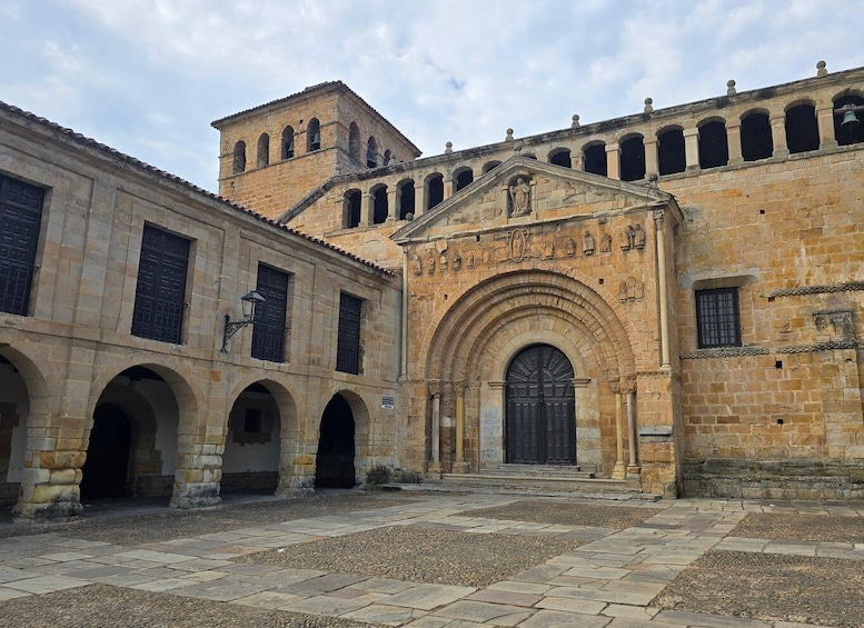 A historic stone building with a central archway, arched windows, and a bell tower. 3